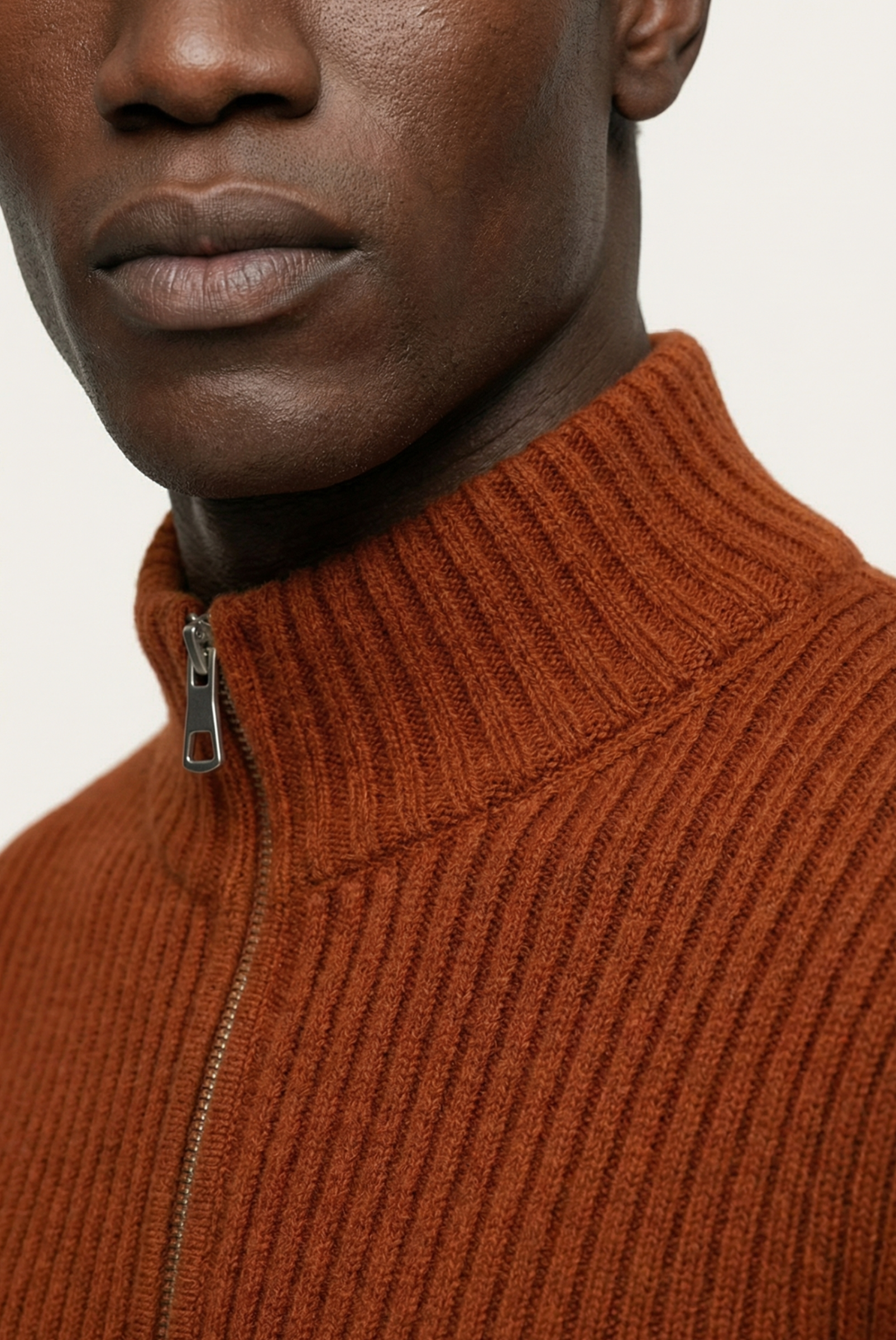 Close-up of a person wearing a brown ribbed sweater with a zipper.