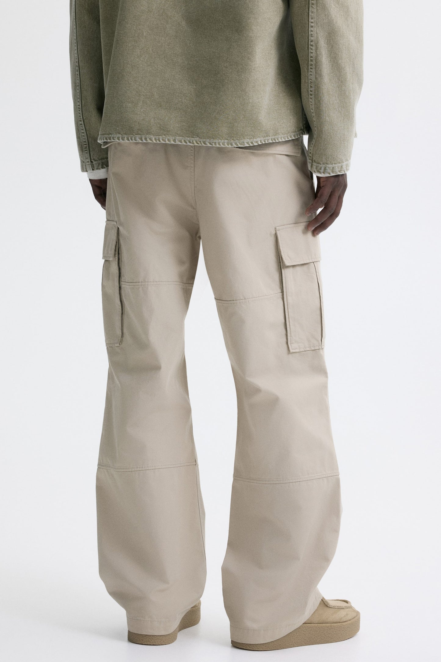 Person wearing beige cargo pants on a white background