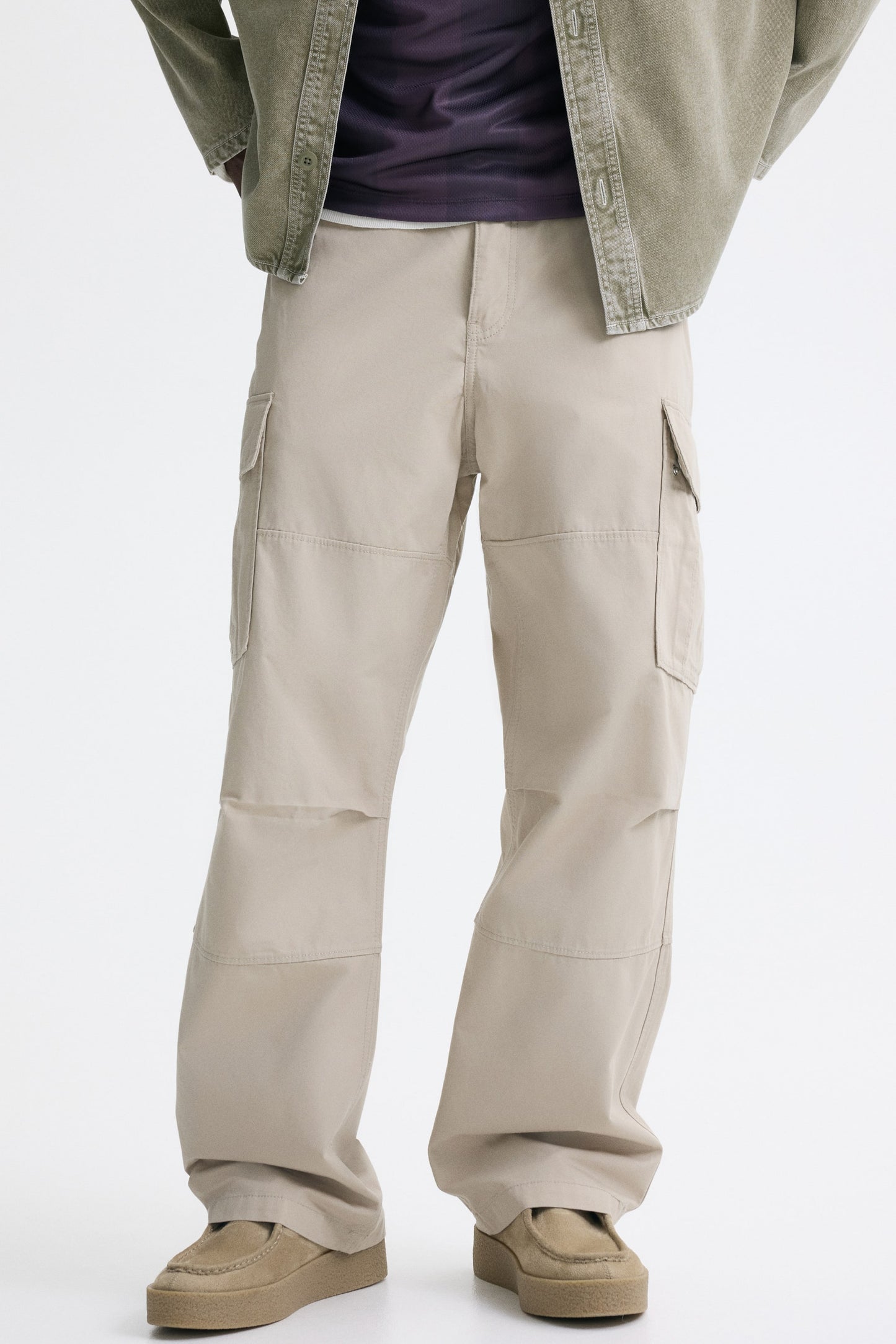 Person wearing beige cargo pants on a white background