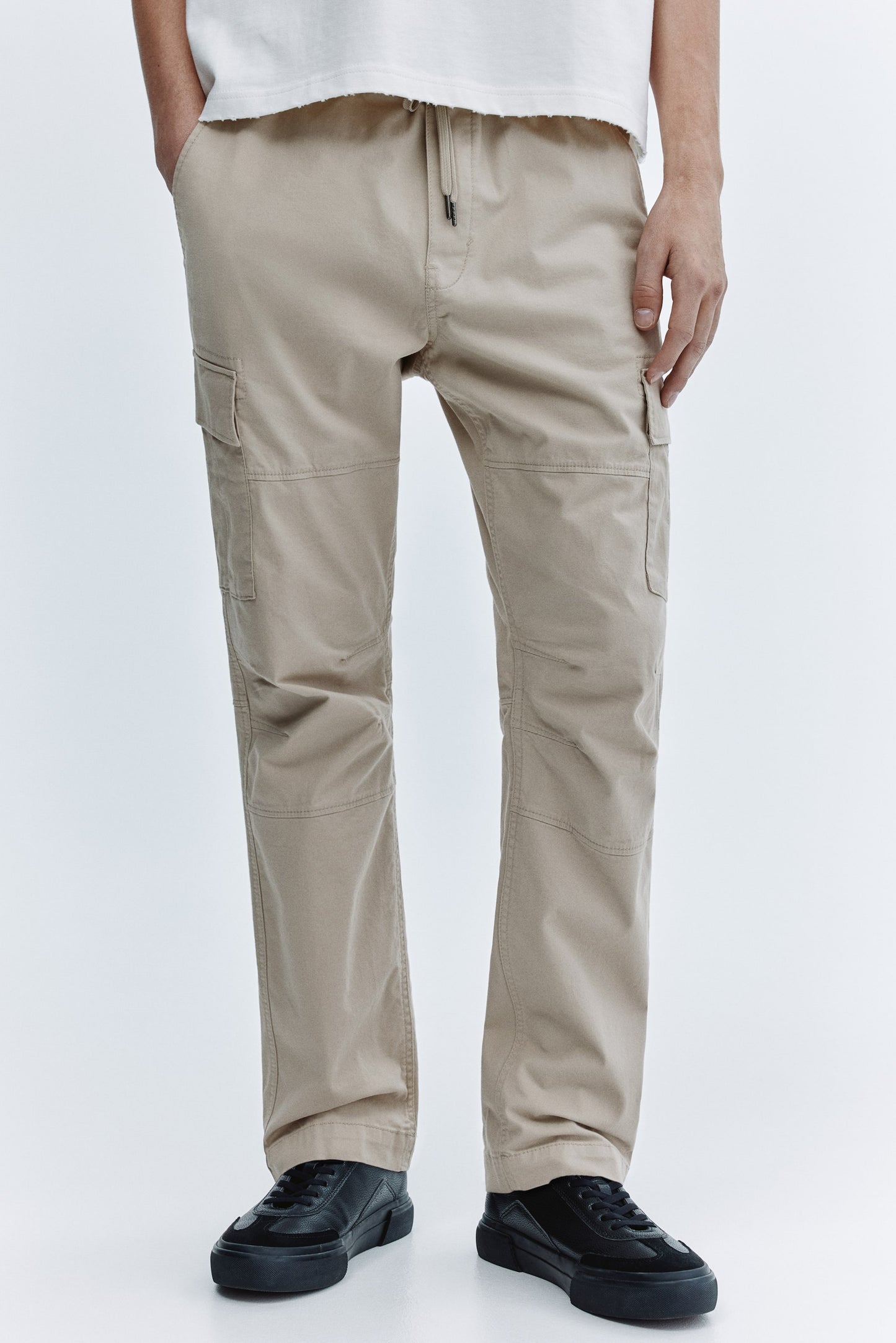 Beige cargo pants worn by a person on a white background