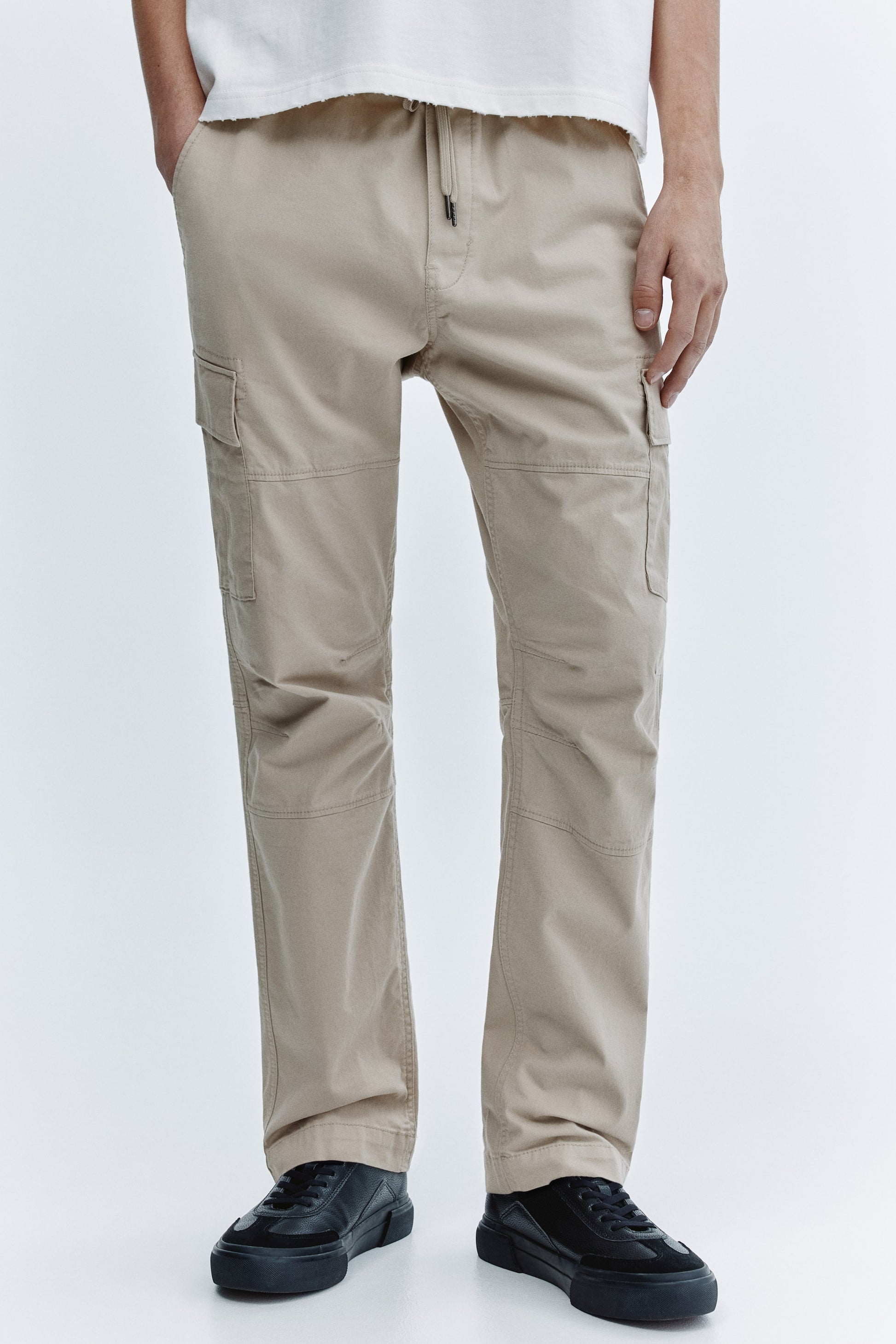 Beige cargo pants worn by a person on a white background