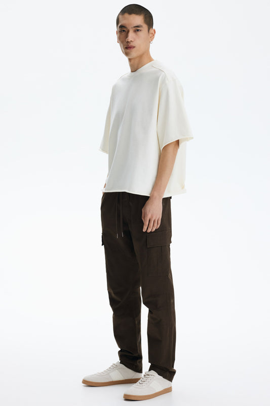 Man wearing a white t-shirt and dark pants on a white background