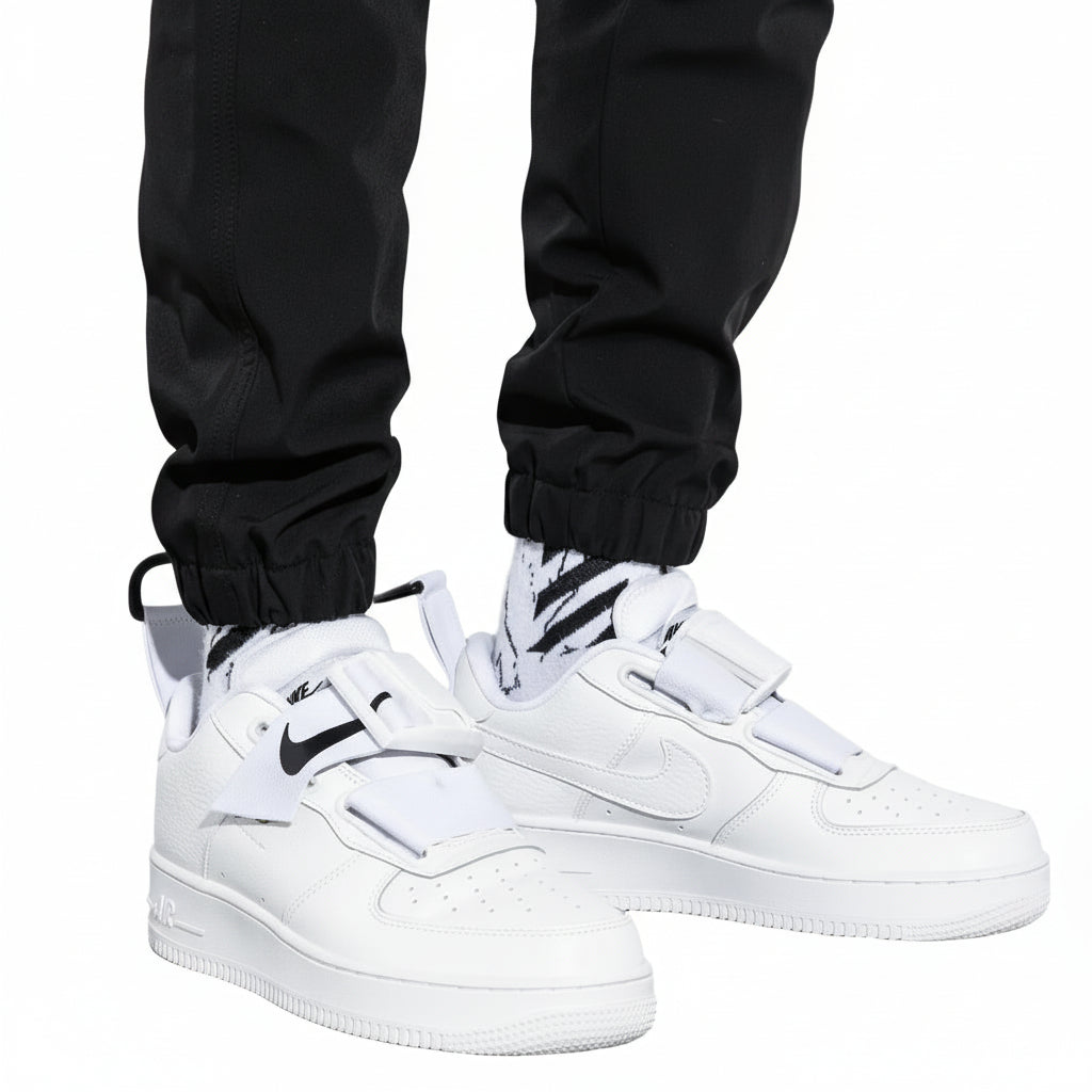 White sneakers with black accents worn with black pants on a white background