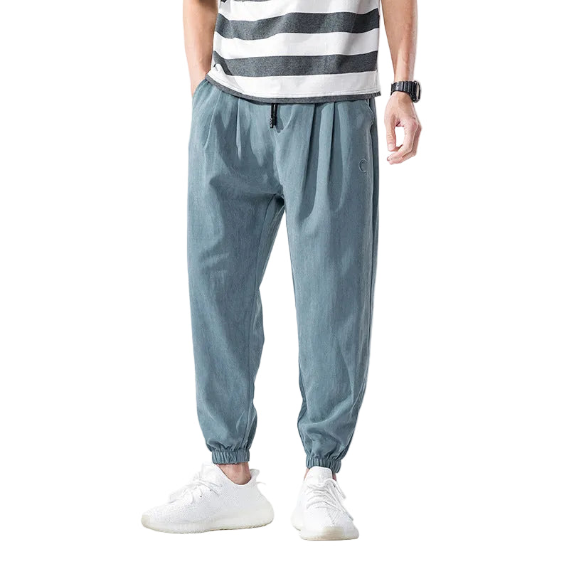Person wearing light blue jogger pants and a striped shirt on a white background