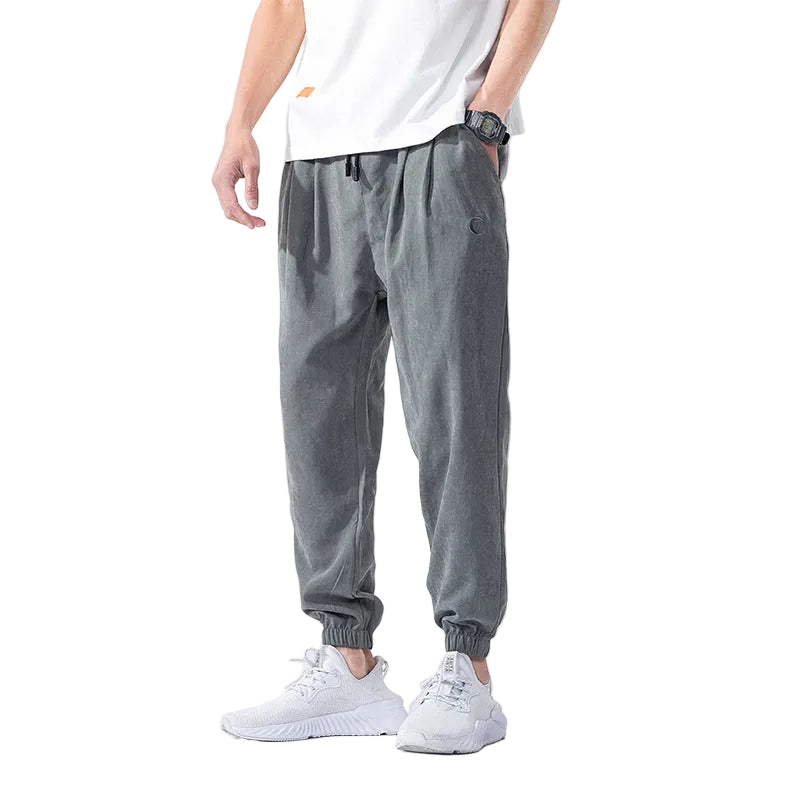 Person wearing gray jogger pants and white sneakers on a white background