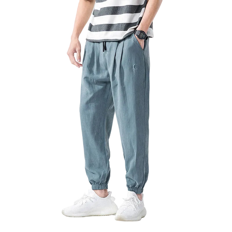 Person wearing light blue jogger pants with a white background
