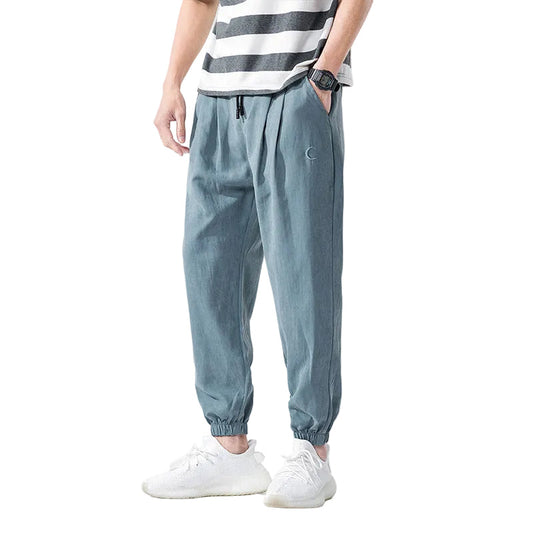 Person wearing light blue jogger pants with a white background